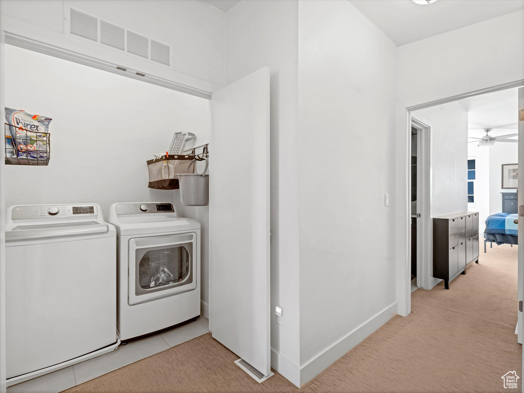 Laundry room with independent washer and dryer, a ceiling fan, light carpet, and baseboards