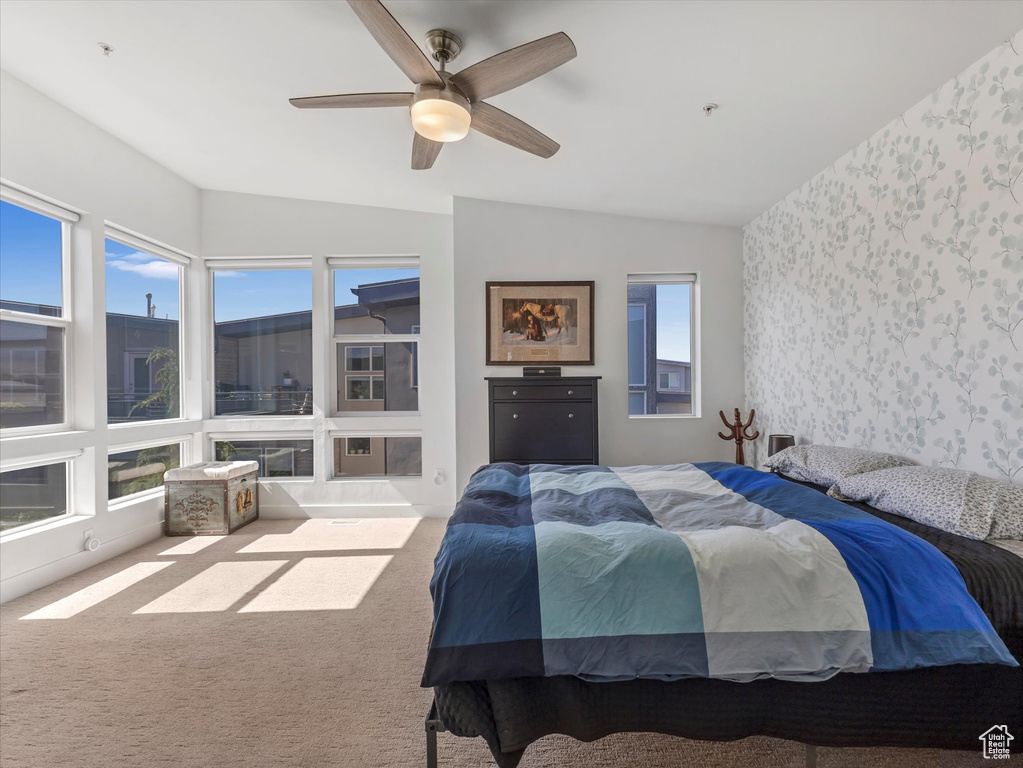 Bedroom featuring wallpapered walls, vaulted ceiling, carpet, and ceiling fan