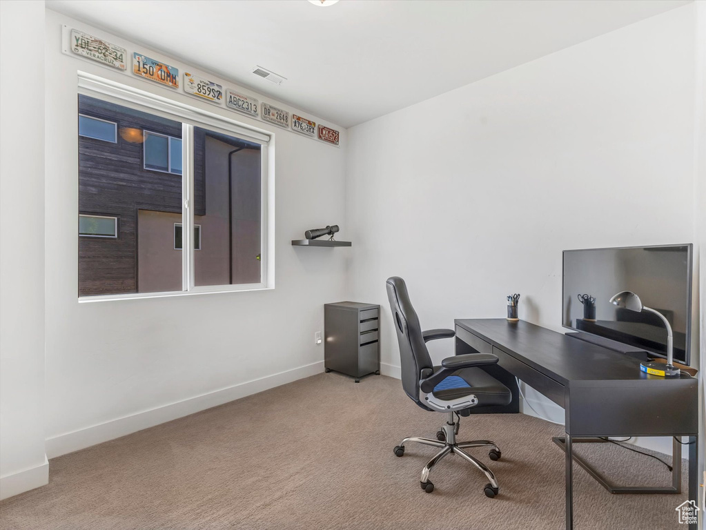 Carpeted home office featuring baseboards