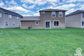 Rear view of house featuring a lawn and stucco siding