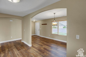 Spare room with arched walkways, wood finished floors, and baseboards