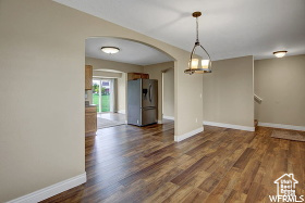 Empty room with arched walkways, wood finished floors, and baseboards