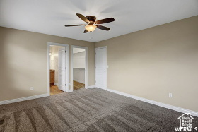 Unfurnished bedroom featuring carpet floors, baseboards, a spacious closet, and a ceiling fan