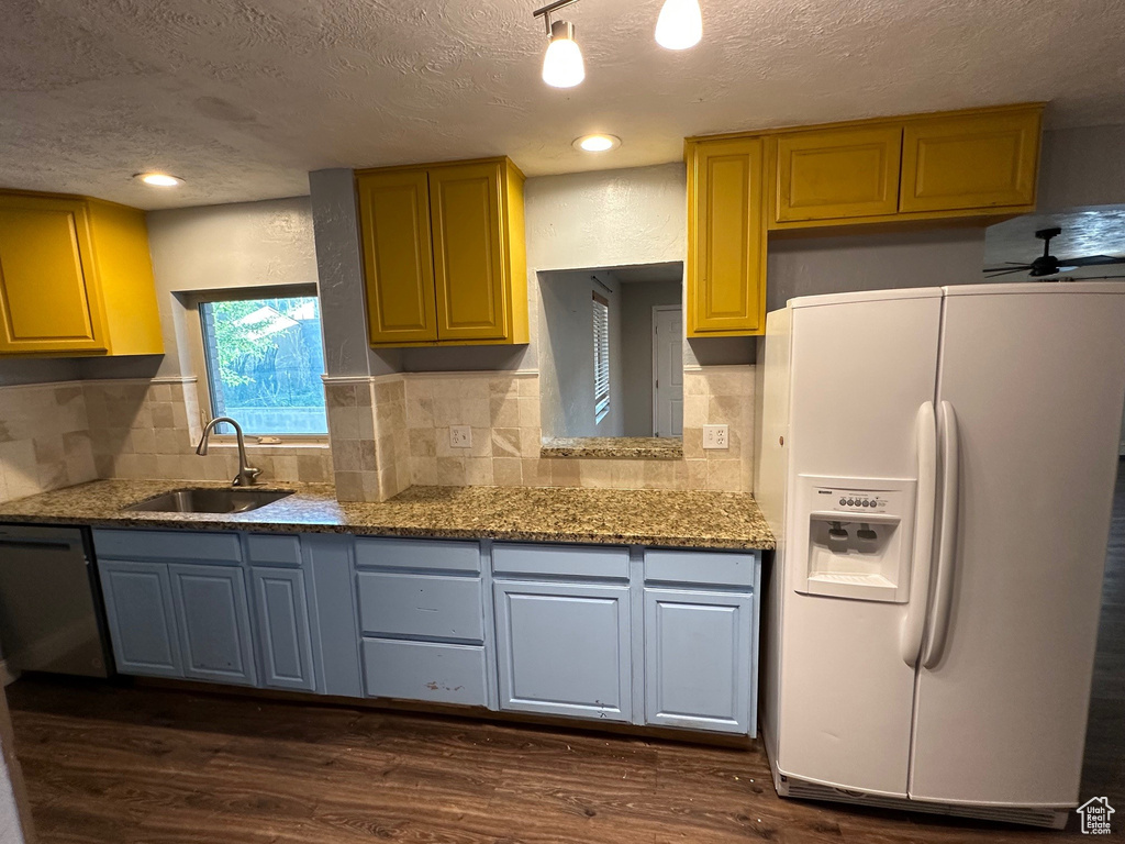 Kitchen with white refrigerator with ice dispenser, a sink, a textured ceiling, dark wood-style floors, and stainless steel dishwasher