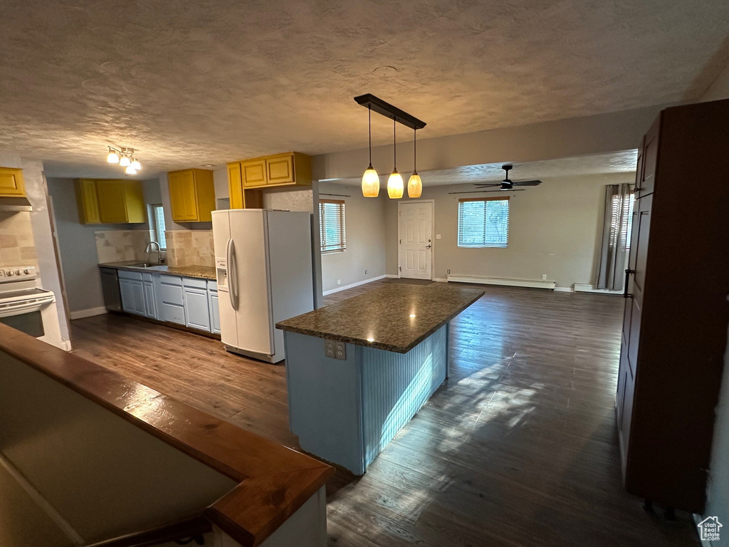 Kitchen with white appliances, a sink, ceiling fan, baseboards, and a textured ceiling