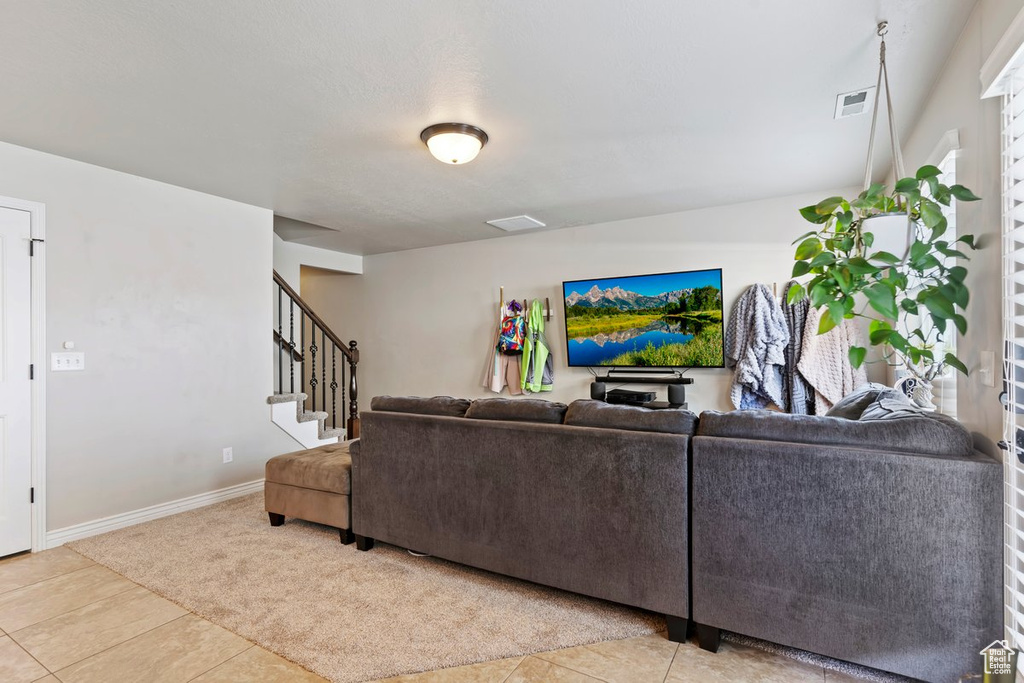 Carpeted living room with tile patterned flooring, stairway, and baseboards