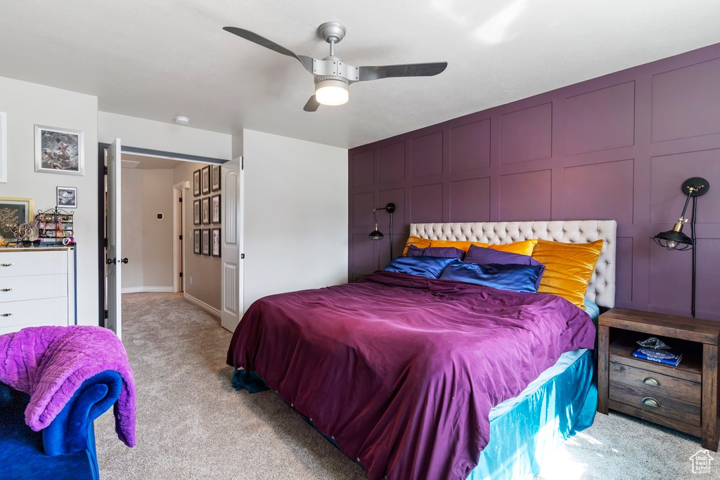 Carpeted bedroom featuring ceiling fan and a decorative wall