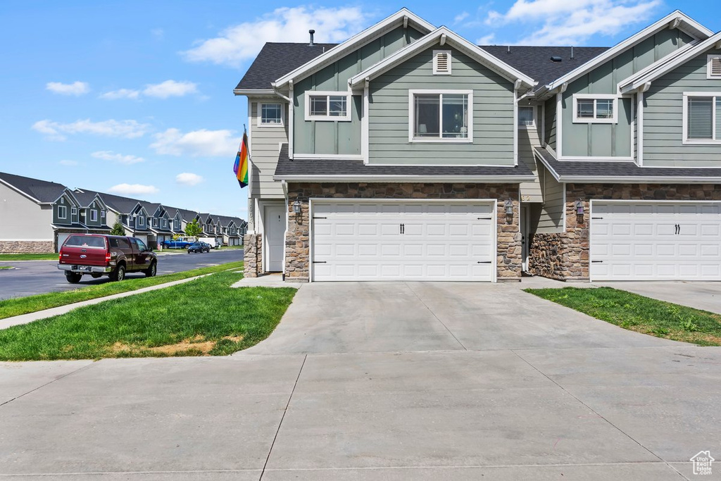 Craftsman-style home with board and batten siding, stone siding, an attached garage, driveway, and a residential view