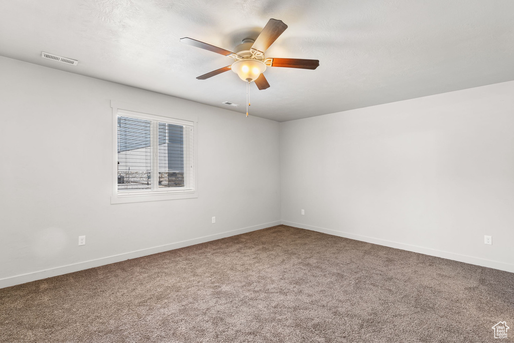 Carpeted empty room with a ceiling fan and baseboards