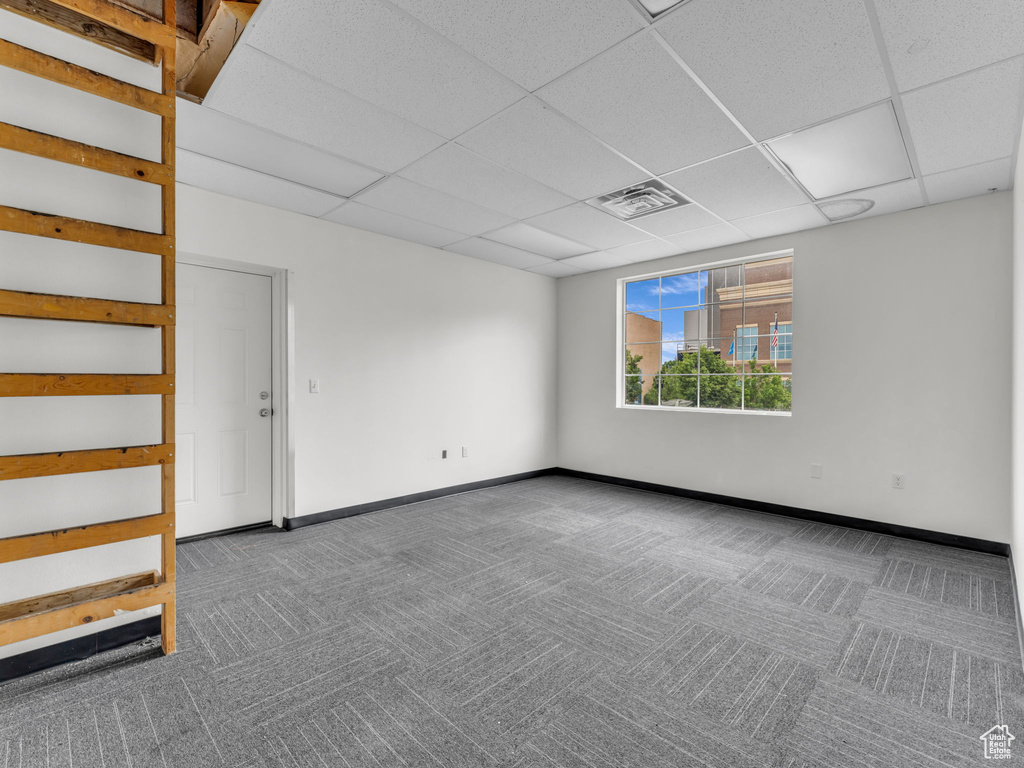 Unfurnished room featuring carpet floors, a paneled ceiling, and baseboards
