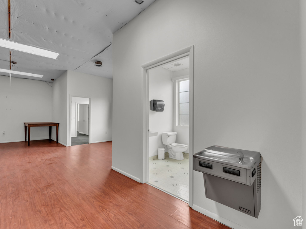 Spare room featuring a skylight, wood finished floors, and baseboards