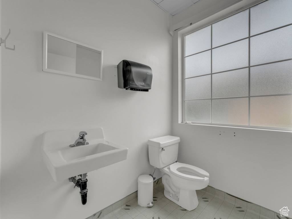 Bathroom with toilet, plenty of natural light, baseboards, and a sink