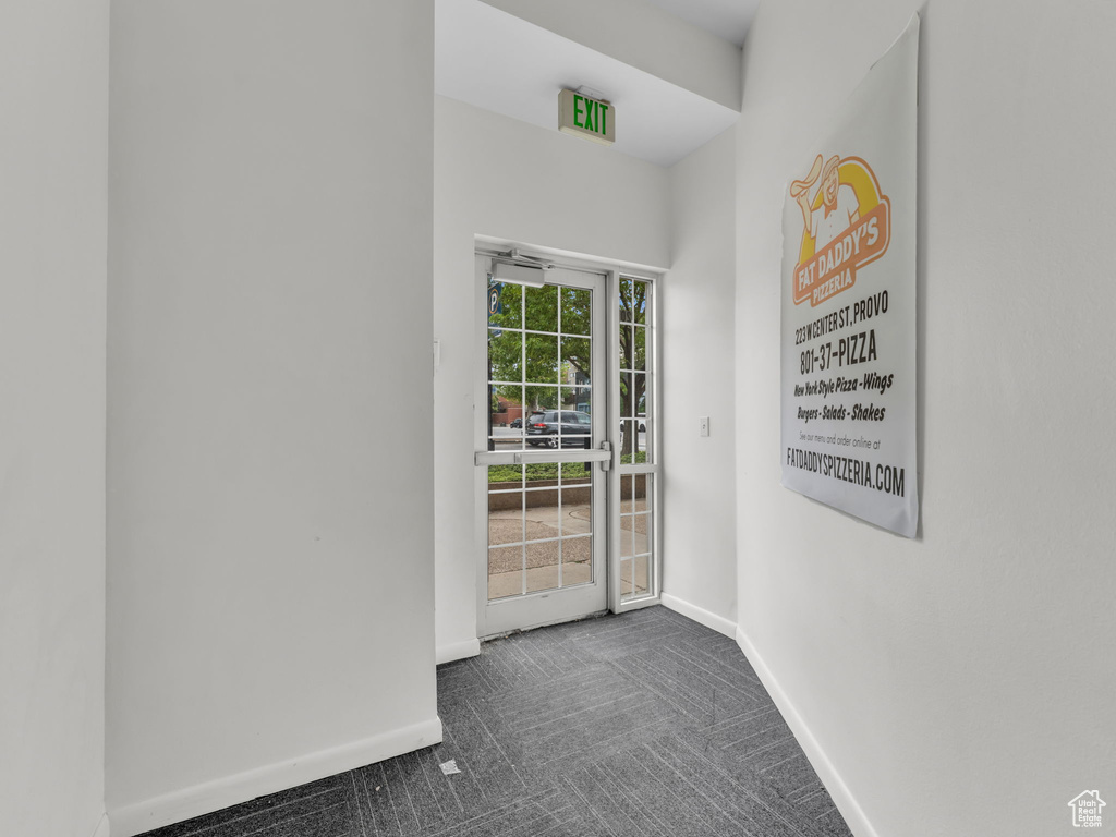 Doorway to outside with dark colored carpet and baseboards