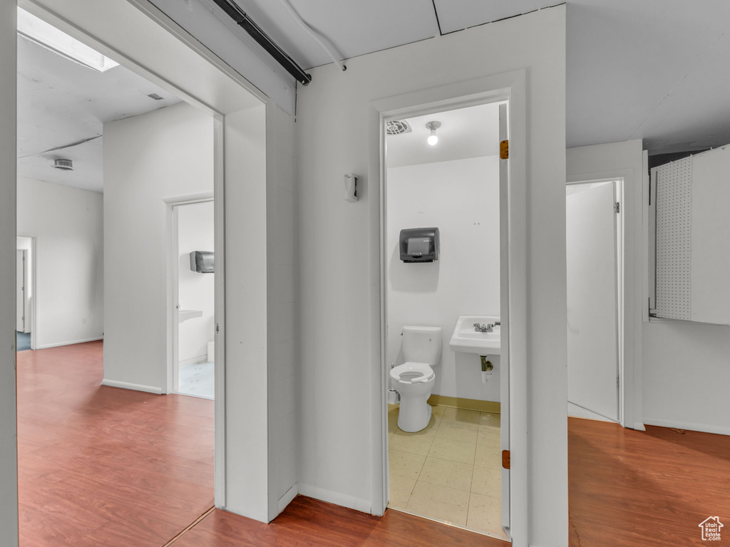 Hall with wood finished floors, baseboards, and a sink