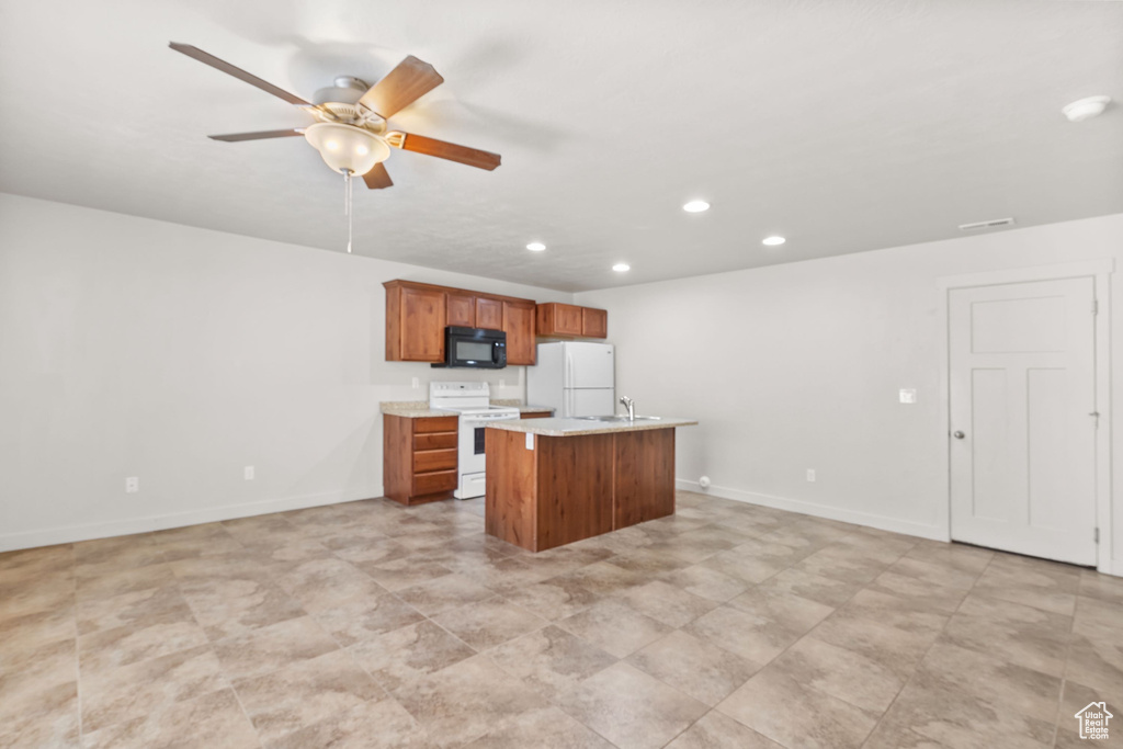Kitchen featuring white appliances, recessed lighting, brown cabinetry, a ceiling fan, and an island with sink