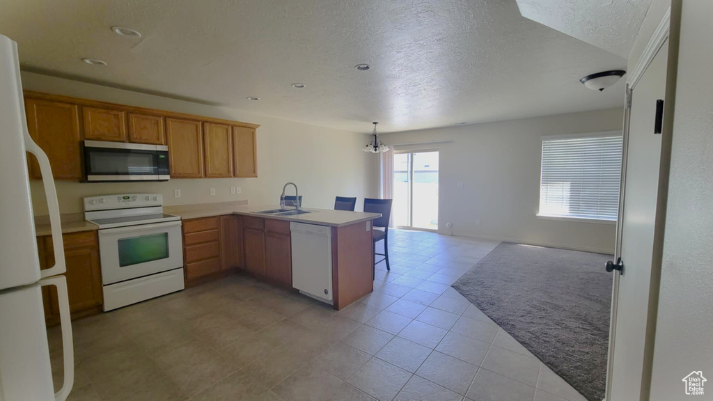 Kitchen with white appliances, a peninsula, a sink, a textured ceiling, and open floor plan