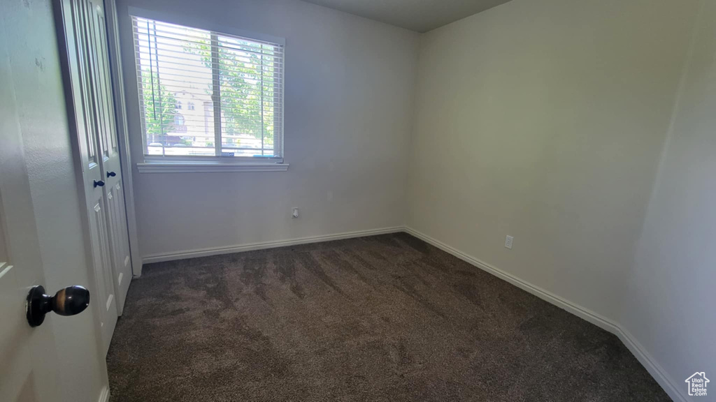Spare room with dark colored carpet and baseboards
