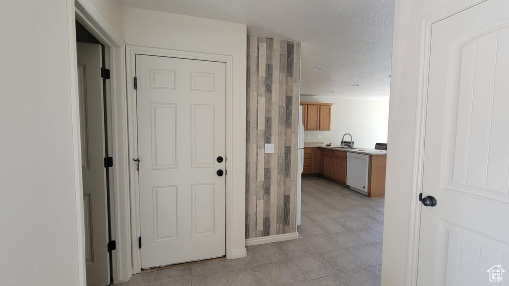 Hall featuring a sink, light tile patterned flooring, and a textured ceiling