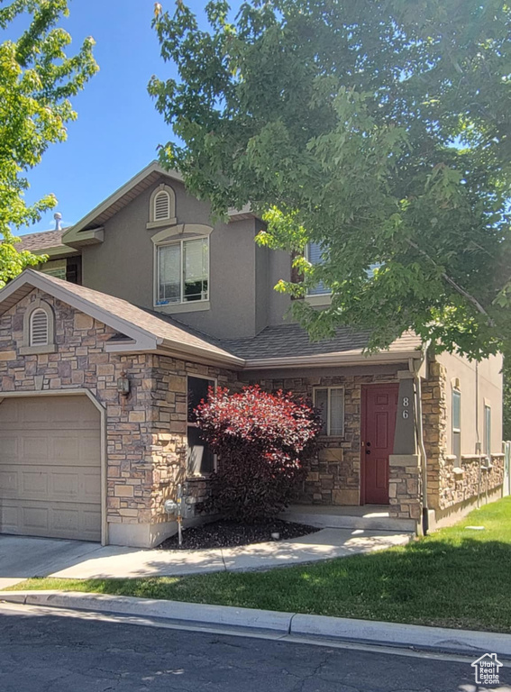 View of front of property with stone siding, stucco siding, and a garage