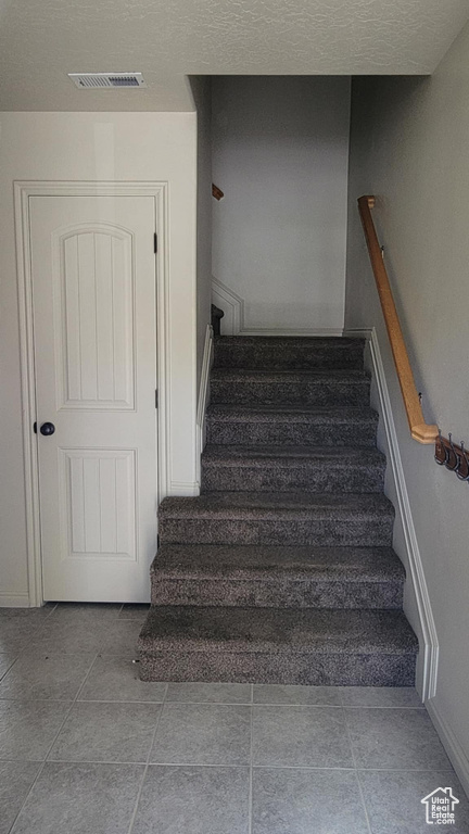 Staircase featuring baseboards and a textured ceiling