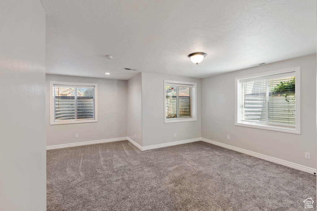 Spare room featuring carpet floors, plenty of natural light, and baseboards