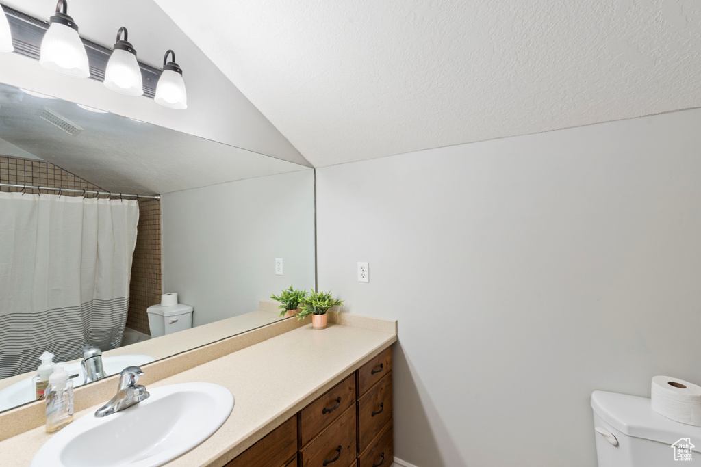 Full bath featuring lofted ceiling, toilet, vanity, and a shower with curtain
