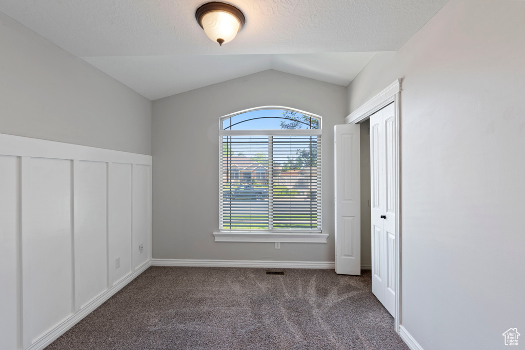 Unfurnished bedroom with carpet and lofted ceiling