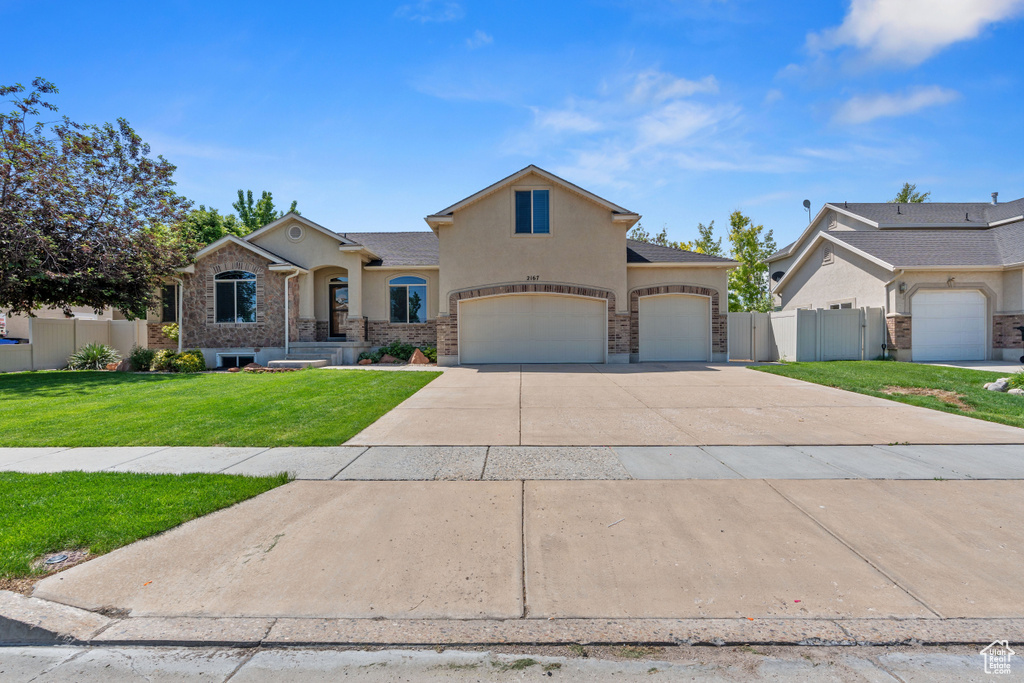 View of front facade featuring stucco siding, driveway, and an attached garage