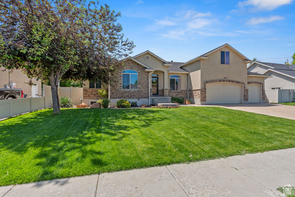 View of front of property featuring stucco siding, driveway, a garage, and stone siding