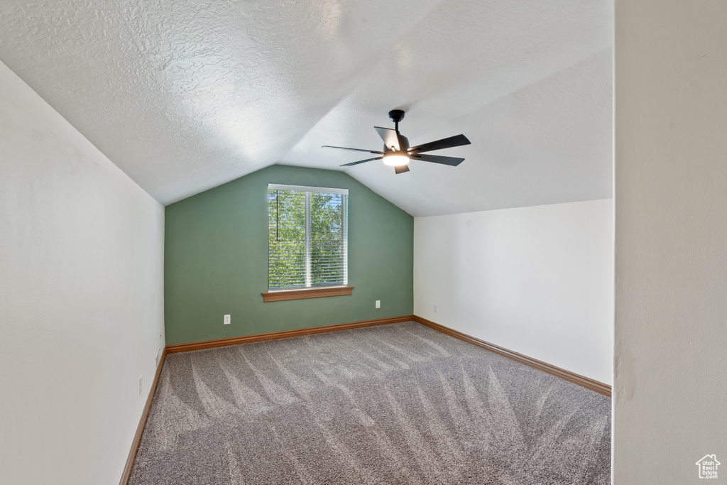 Bonus room with carpet, ceiling fan, lofted ceiling, baseboards, and a textured ceiling