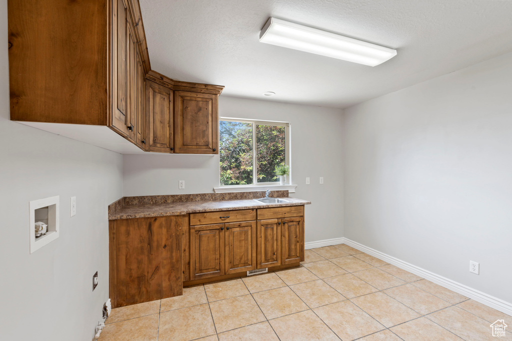 Laundry area with cabinet space, washer hookup, baseboards, and light tile patterned floors