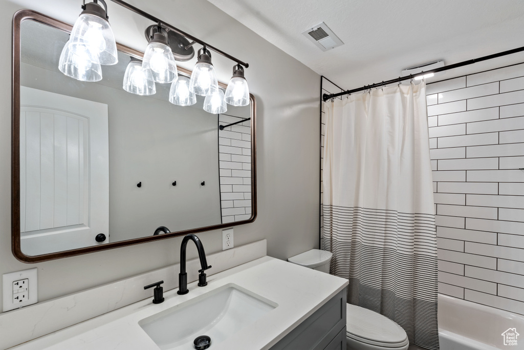 Bathroom with toilet, vanity, and shower / bath combo with shower curtain