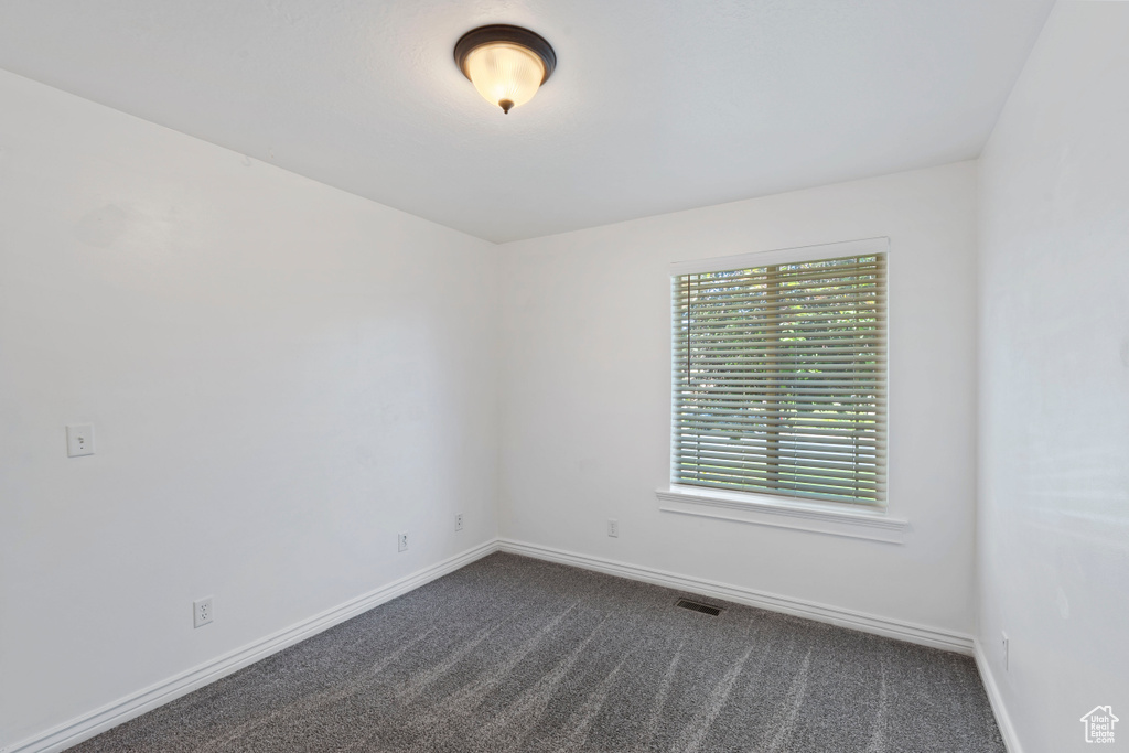 Empty room featuring dark colored carpet and baseboards