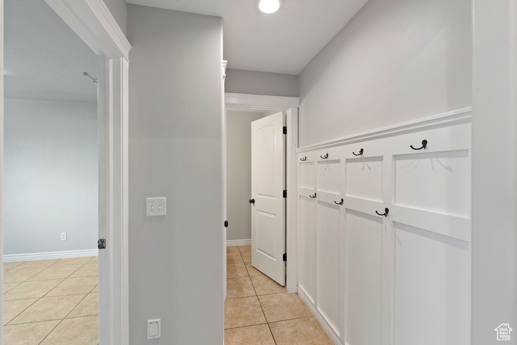 Corridor with light tile patterned flooring and baseboards