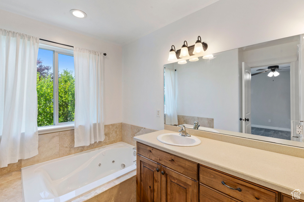 Bathroom featuring vanity, a tub with jets, and a ceiling fan