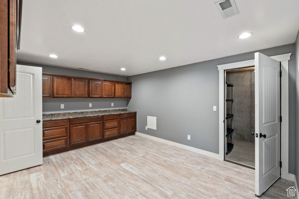 Kitchen with light wood finished floors, recessed lighting, baseboards, and brown cabinetry