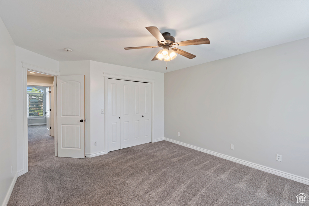 Unfurnished bedroom featuring carpet floors, baseboards, a closet, and ceiling fan