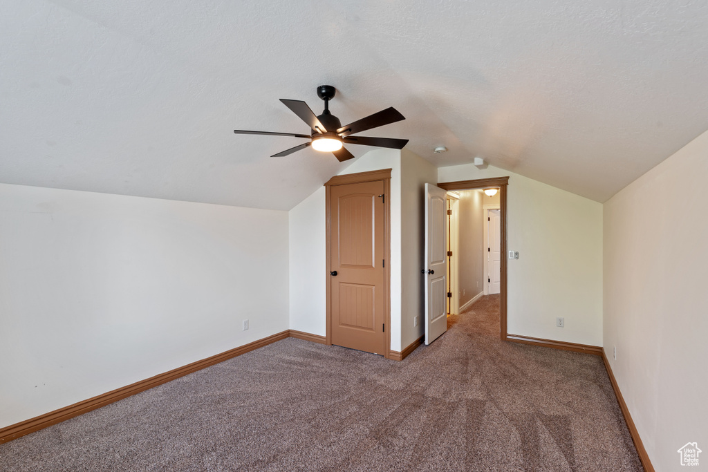 Additional living space with carpet floors, lofted ceiling, ceiling fan, and baseboards