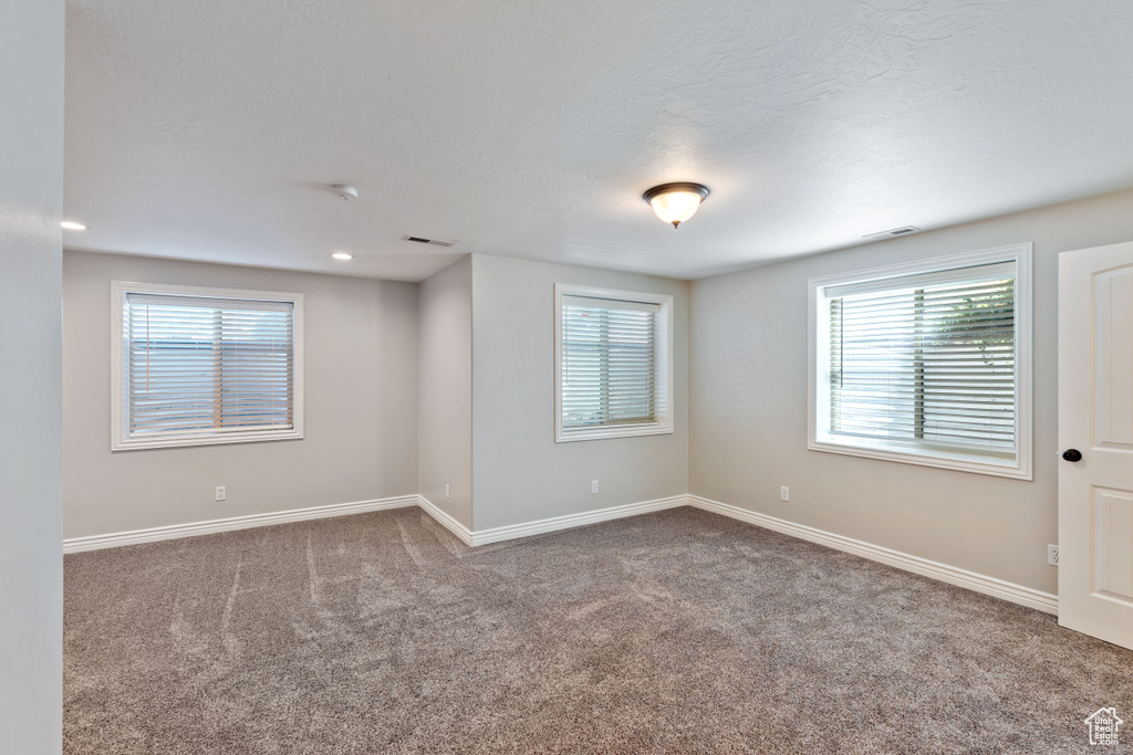 Empty room with carpet, healthy amount of natural light, and baseboards
