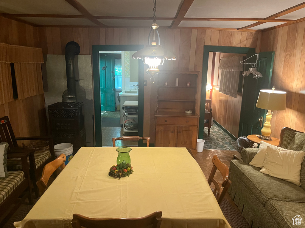 Dining room with wooden walls, a wood stove, and beam ceiling