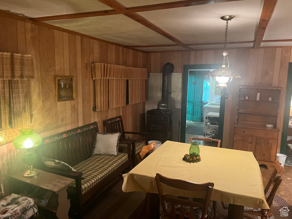 Dining space featuring wooden walls, a wood stove, and beam ceiling