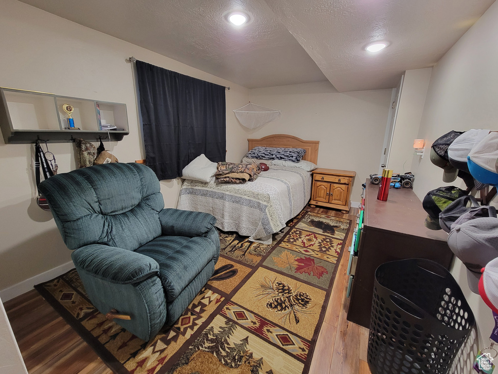 Bedroom featuring wood finished floors, recessed lighting, baseboards, and a textured ceiling