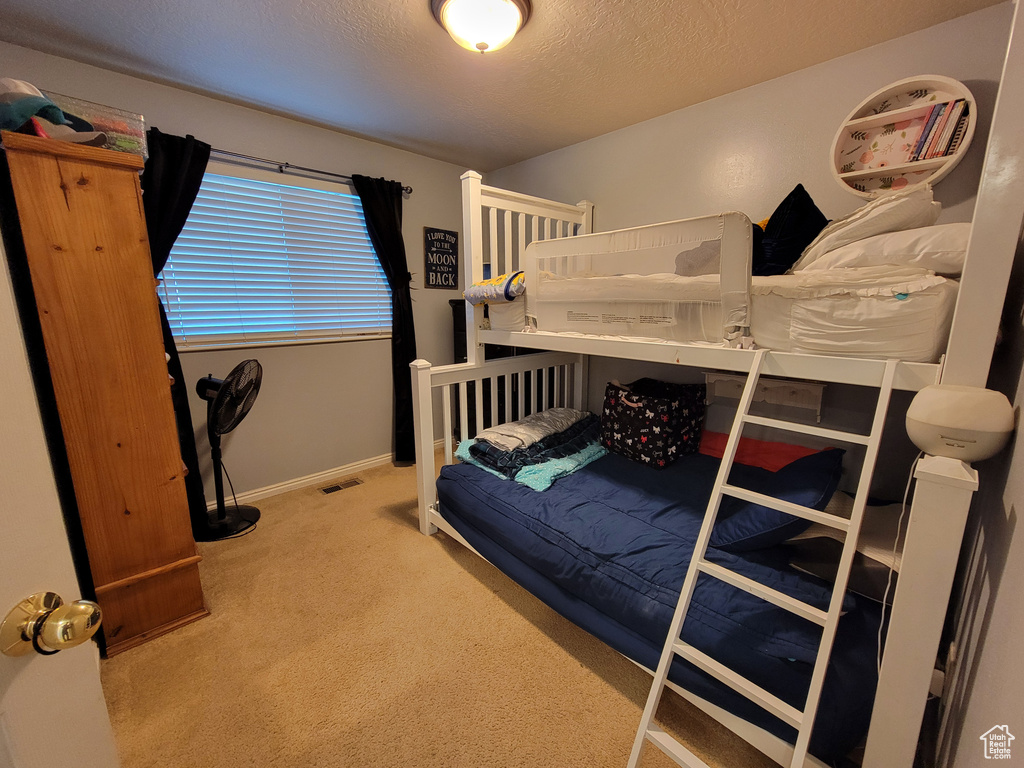 Bedroom with carpet, a textured ceiling, and baseboards