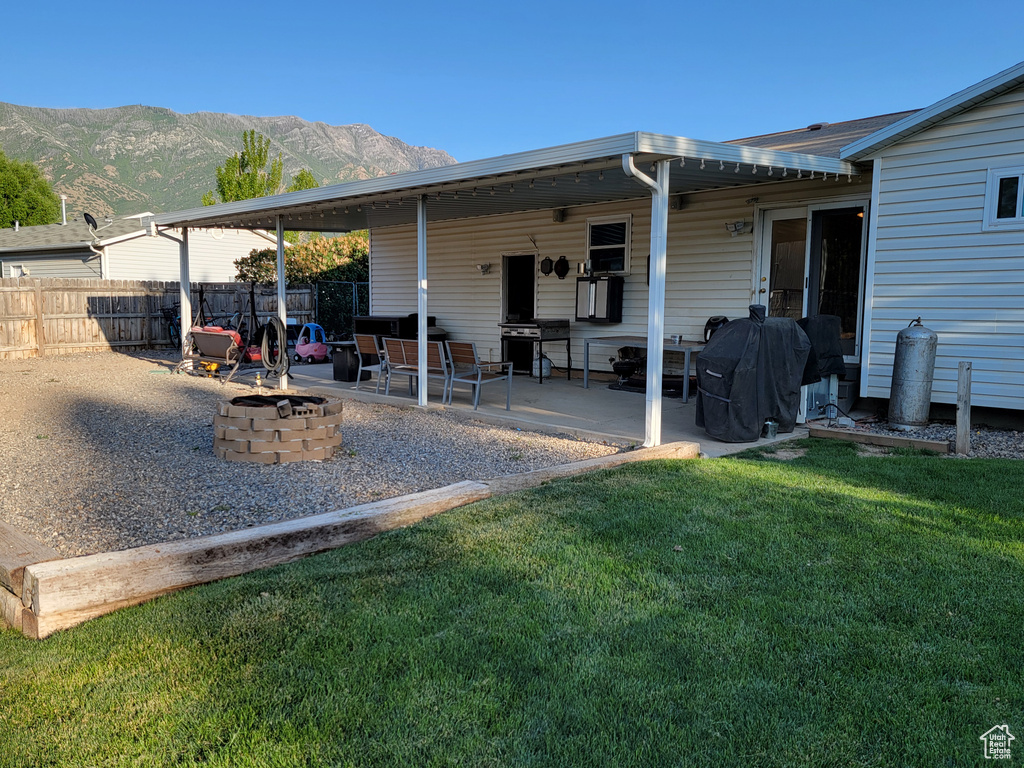 Rear view of property with a fire pit, a mountain view, and a patio area