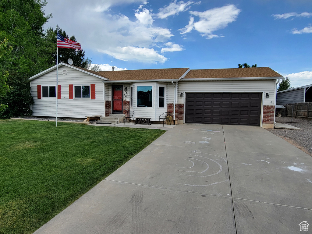 Ranch-style house featuring driveway, an attached garage, a front lawn, and brick siding
