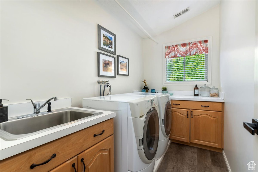 Laundry area with washing machine and clothes dryer, cabinet space, and dark wood finished floors