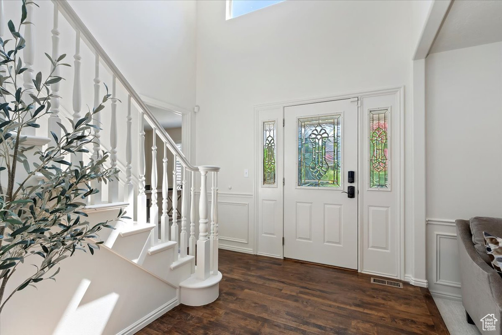 Foyer with plenty of natural light, wood finished floors, a decorative wall, wainscoting, and stairs