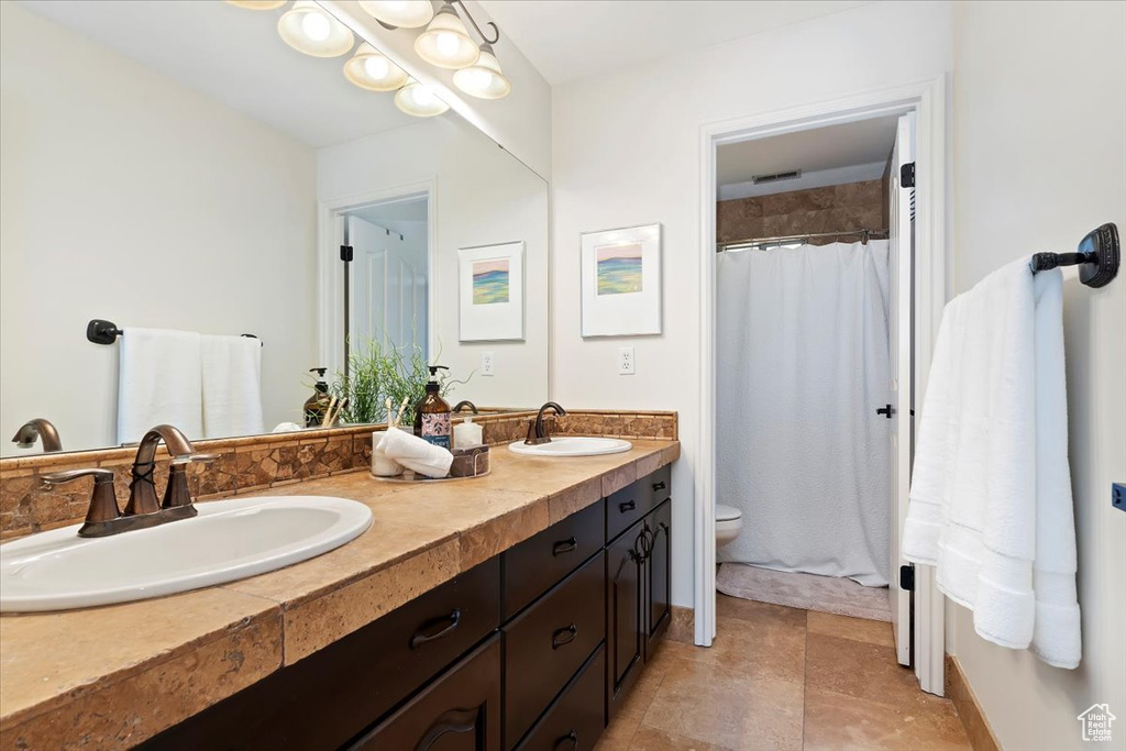 Full bathroom with double vanity, toilet, and a shower with curtain