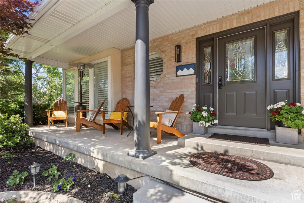 View of exterior entry with covered porch and brick siding