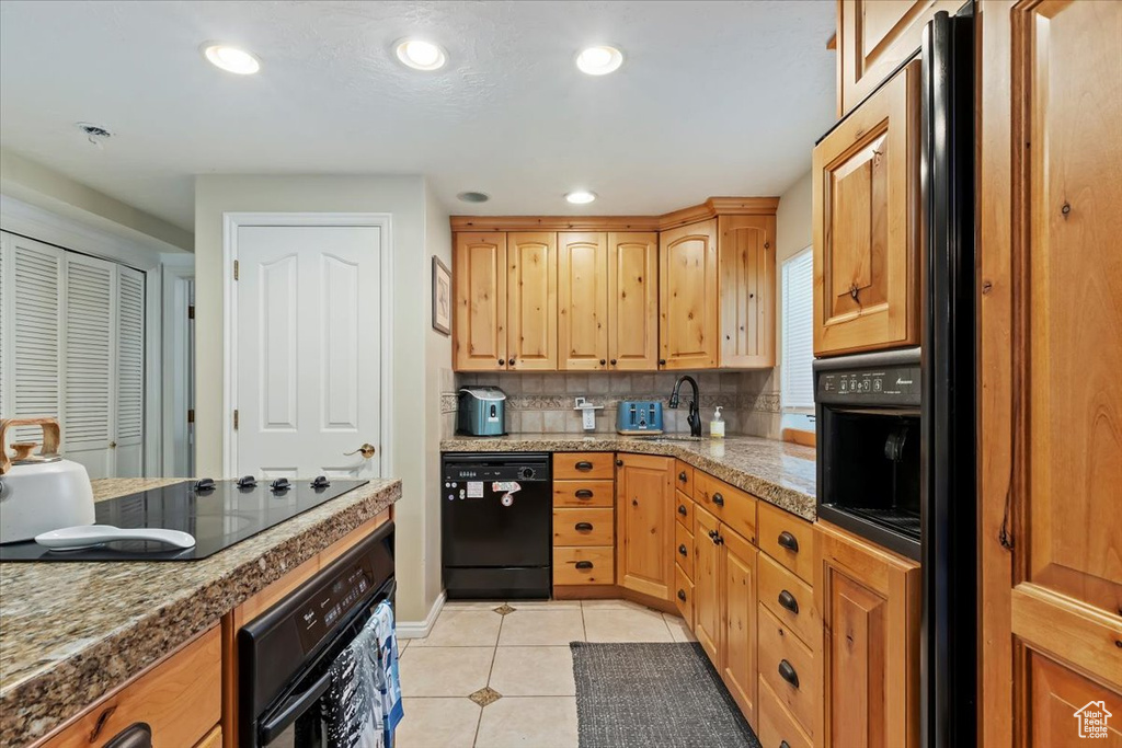 Kitchen featuring black appliances, a sink, light tile patterned floors, decorative backsplash, and recessed lighting